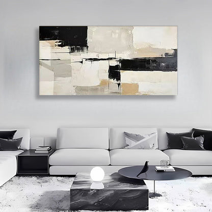 A large abstract canvas wall art print with black, beige, and white brushstrokes, displayed in a modern living room setting above a white sofa.