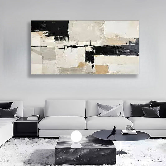 A large abstract canvas wall art print with black, beige, and white brushstrokes, displayed in a modern living room setting above a white sofa.